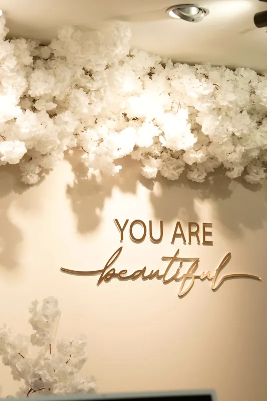 Wand mit dem Schriftzug You are beautiful unter weißen Blüten